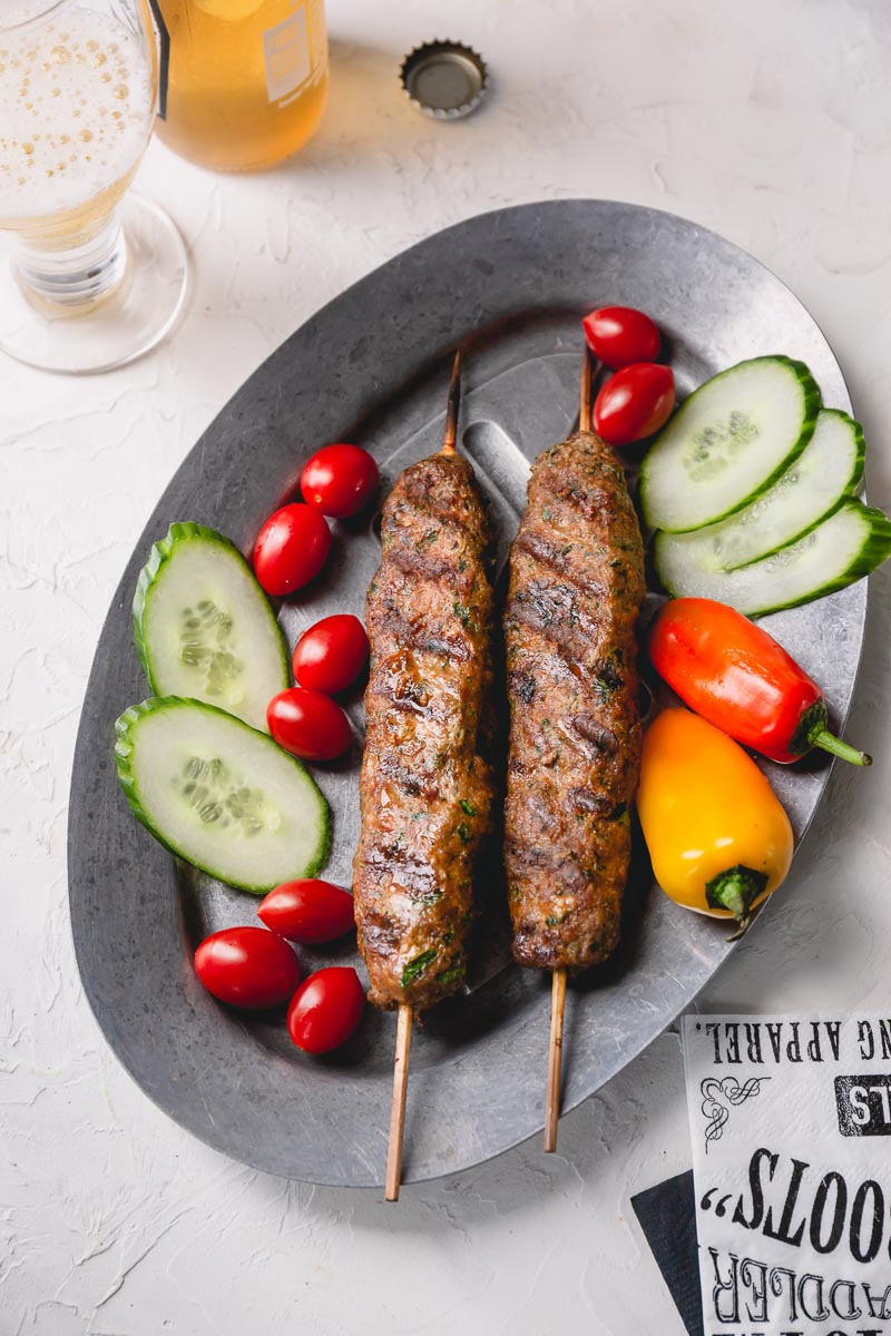 Turkish Urfa kebabs (ground beef) on warm **naan bread with an assortment of grilled, shishito pepper, banana peppers, and tomatoes